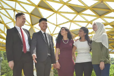 Five people interacting beneath a yellow geometric structure, from a TAPiO intern photo session.
