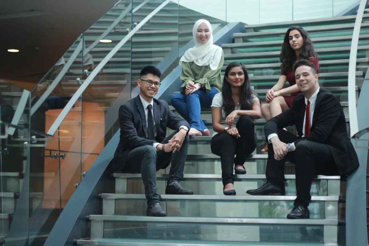 Five people seated together on a staircase, from a TAPiO intern photo session.